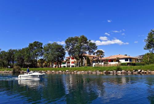 a man in a boat on a river with houses at Hotel Casarose - Cannes Mandelieu in Mandelieu-la-Napoule