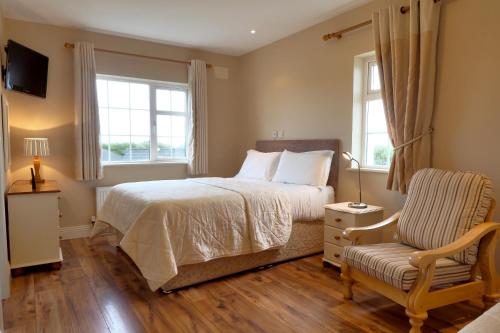 a bedroom with a bed and a chair and a window at Hillcrest Luxury Apartment in Kilrush