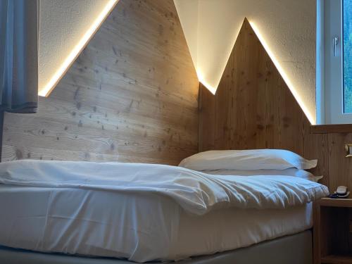 a bedroom with a bed with a wooden wall at Fedaia Joy B&B in Canazei