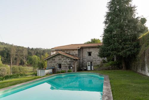 ein großer Pool vor einem Steinhaus in der Unterkunft Quinta de Pindela - Natureza e Tradicao in Vila Nova de Famalicão