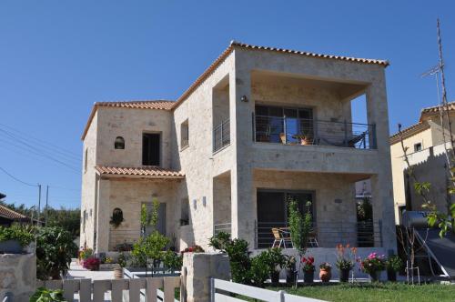una gran casa de piedra con una valla delante en Liri's Apartments, en Kalamaki
