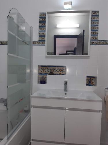 a white bathroom with a sink and a mirror at Pedras d'el Rei - Casa Mira in Tavira