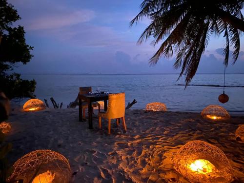 a table and chairs on the beach at night at Veli Beach Inn in Mathiveri