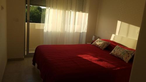a bedroom with a red bed with a window at Apartment Janja in Medulin