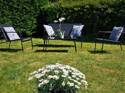 three chairs and a table in the grass with flowers at ENTRE TERRE ET MER in Blonville-sur-Mer