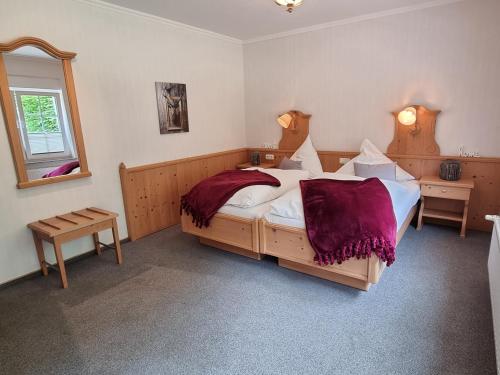 a bedroom with a large bed with burgundy sheets at Landhotel Hof Barrl in Schneverdingen