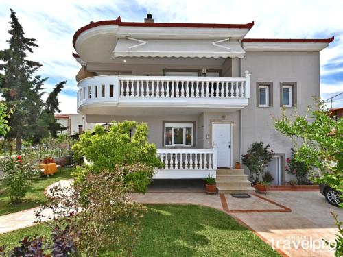 a white house with a balcony and a yard at Villa Vangelis in Nea Plagia