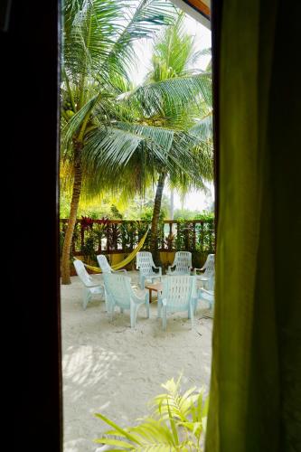 a table and chairs on a beach with palm trees at Veli Beach Inn in Mathiveri