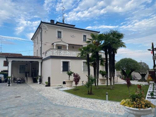 a white building with palm trees in front of it at B&B STAZIONE DON CAMILLO in Brescello