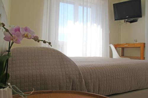 a bedroom with a bed and a vase with flowers at Hotel Sole in Cannero Riviera