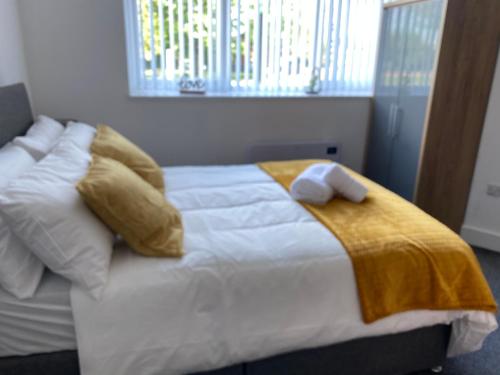 a white bed with a yellow blanket and pillows at 2A SPV Double En-suite Room in Wakefield