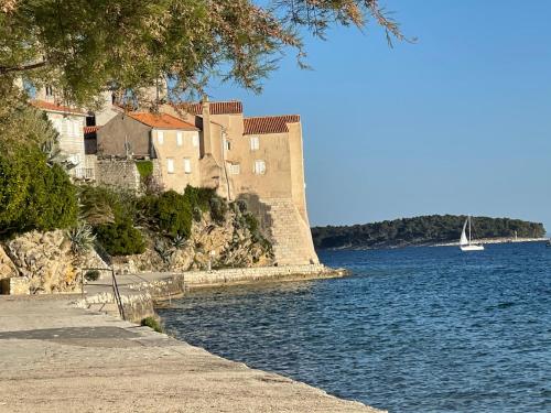 a building on the side of a river with a sailboat at Elena in Rab