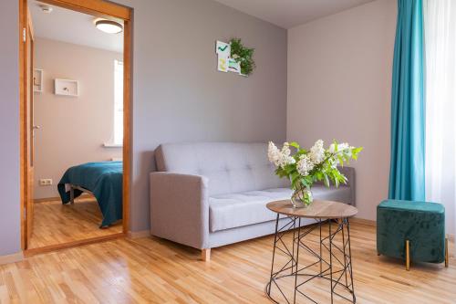 a living room with a couch and a table with flowers at Kurshi Hotel & Spa in Jūrmala