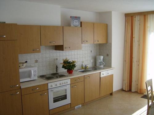 eine Küche mit Holzschränken, einer Spüle und einer Mikrowelle in der Unterkunft Haus Josefine in Gerlos