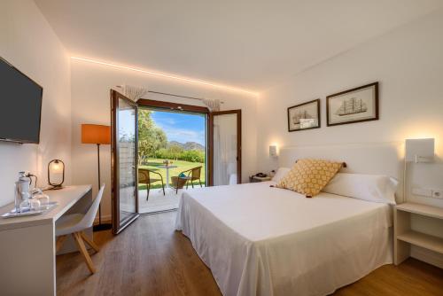 Schlafzimmer mit einem Bett, einem Schreibtisch und einem Fenster in der Unterkunft Son Corb Boutique Hotel in Cala Bona