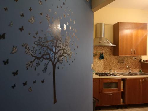 a kitchen with a tree stenciled on the wall at La casa di Nina in San Giovanni la Punta