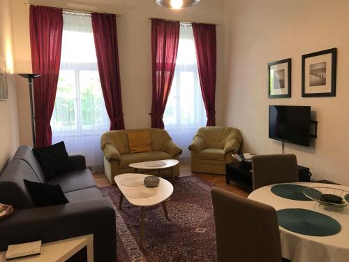 a living room with a couch and chairs and a tv at Apartment Sadova in Karlovy Vary