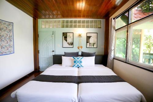 Evergreen Pakchong Home في باك تشونغ: سريرين في غرفة بها نافذتين