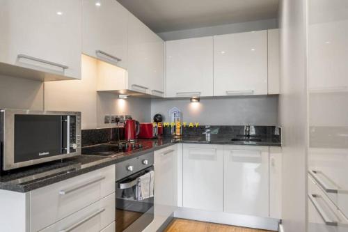a kitchen with white cabinets and a microwave at 1BR Apt Near Heathrow By Tempstay in Slough