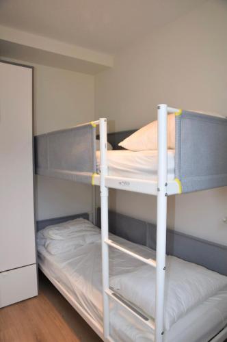 two bunk beds in a small room with a door at Sea View Penthouse in De Panne