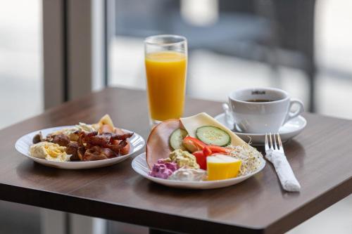 a table with two plates of food and a cup of orange juice at Cameo Boutique Hotell in Ystad