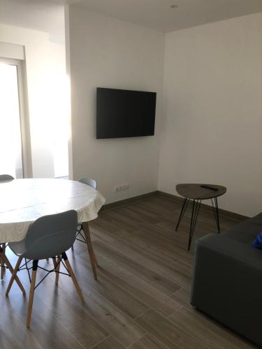 a living room with a table and a tv on a wall at Sollaris Appartements RDC à 11km de Europa-Park in Friesenheim