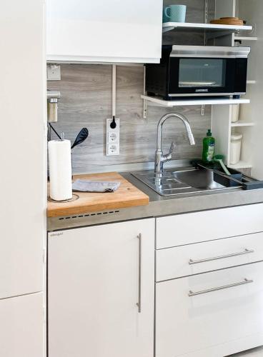 a white kitchen with a sink and a microwave at WellenRausch Living "Nock" in Travemünde