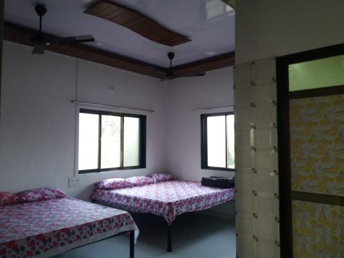 Zimmer mit 2 Betten und 2 Fenstern in der Unterkunft Mill House in Alibag