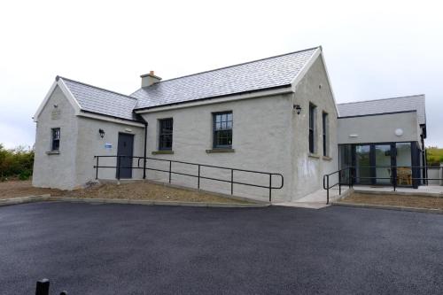 a large white house with a parking lot at Whiddy School House Accommodation in Ladyʼs Odell
