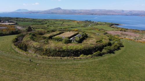 an island in the middle of a field next to the water at Whiddy School House Accommodation in Ladyʼs Odell
