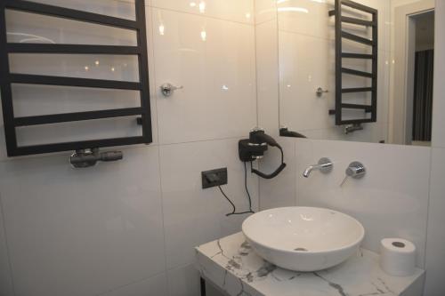een witte badkamer met een wastafel en een spiegel bij Atmosfera Apartament 3 in Bytów