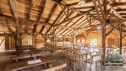 - un grand bâtiment en bois avec des tables et des chaises dans l'établissement Almdorado, à Übersee