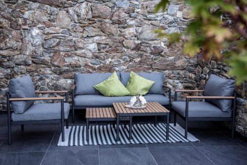 a couch and two chairs and a table in front of a stone wall at Apartment Schifta in Chienes