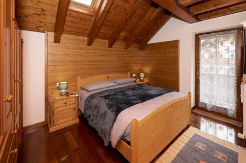 um quarto com uma cama num quarto de madeira em Larici Rooms em Roana