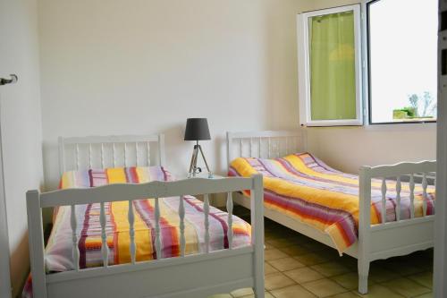 2 Einzelbetten in einem Zimmer mit Fenster in der Unterkunft Maison idéale pour des vacances en famille revigorantes à Brem-sur-Mer in Brem Sur Mer