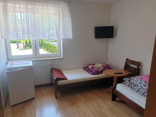 een kamer met een bed, een tafel en een raam bij POKOJE U MIKOŁAJA in Kamień Pomorski