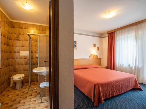 a hotel room with a bed and a bathroom at Hotel Adriana in Alleghe