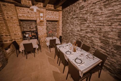 a dining room with tables and chairs and a brick wall at Dzveli Ubani in Sighnaghi