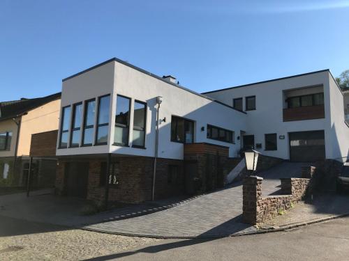 a large white house with a brick driveway at Ferienwohnung Südkurve in Briedel