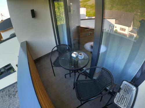 a balcony with a table and chairs and a window at Ferienwohnung Südkurve in Briedel
