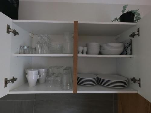 a kitchen shelf with plates and dishes on it at Ferienwohnung Südkurve in Briedel