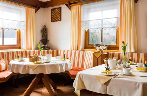 a dining room with two tables and two windows at Gästehaus Fitsch in Obsteig