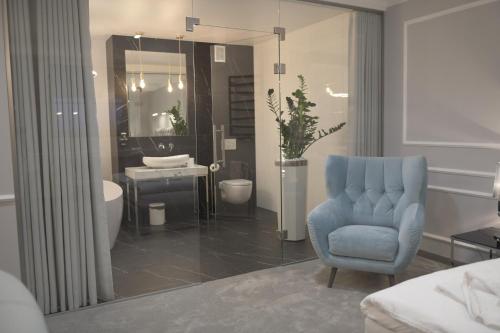 uma casa de banho com uma cadeira azul, um lavatório e um espelho. em Atmosfera Apartament 4 em Bytów