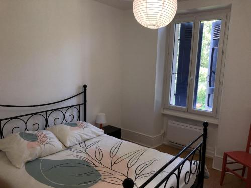 a bedroom with a bed and a window and a chandelier at Chambres individuelles avec partie commune ou logement entier si disponible Via Rhôna in Vulbens