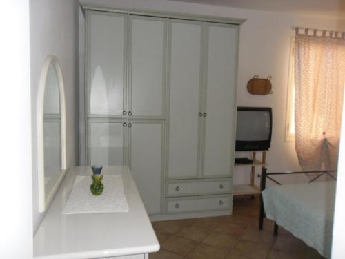 a white cabinet with a vase on a table in a room at Appartamenti Claudia Rio in Rio Marina
