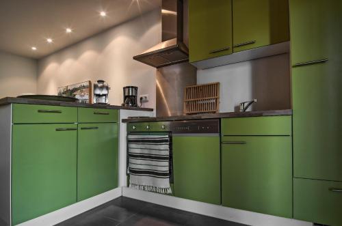 a kitchen with green cabinets and a stove at Le Mas Du Pont Roman in Mane