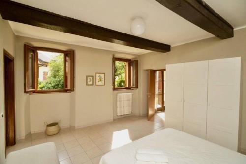 una camera con un letto bianco e due finestre di Contempora Apartments - Ca' Brenta Garden a San Fedele Intelvi
