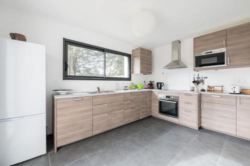 une cuisine avec des placards en bois et une grande fenêtre dans l'établissement Maison neuve pour 4 adultes - 2 enfants - Jardin, à Piriac-sur-Mer