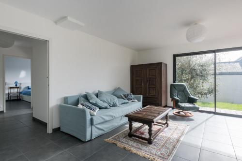 a living room with a couch and a chair at Une belle maison ouverte sur le jardin, près de la mer in Piriac-sur-Mer