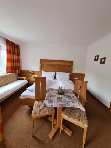 a bedroom with a bed and a table and chairs at Pension Appartementhaus Bergland in Biberwier